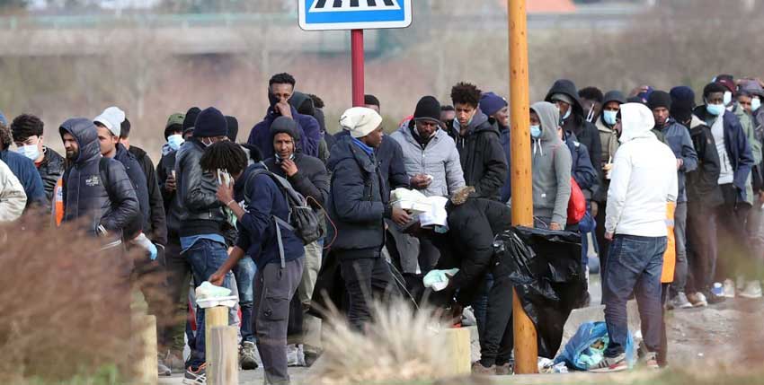 refugees wait in a line to receive food aid in Calais